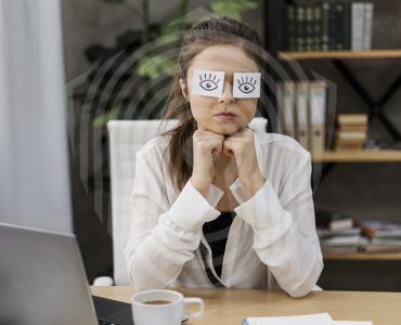 young-businesswoman-covering-her-eyes-with-drawn-eyes-paper